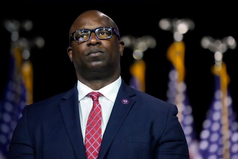 Jamaal Bowman stands in front of five partially visible American flags.