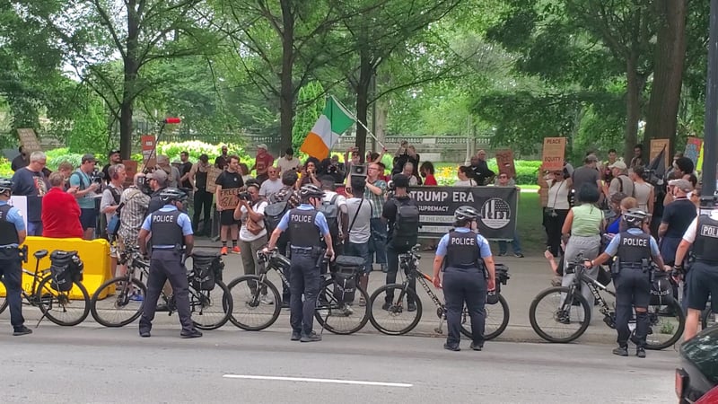 Protestors hold signs behind a line of police and bicycles.
