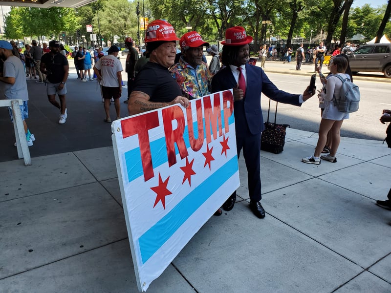 Three men pose with a homemade version of the Chicago flag that reads "Trump."