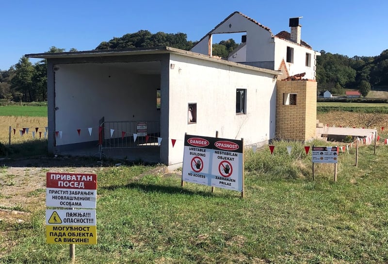 A house that demolished during Jadar mine project in Serbia. It's sitting in a green field, with warning signs out front.
