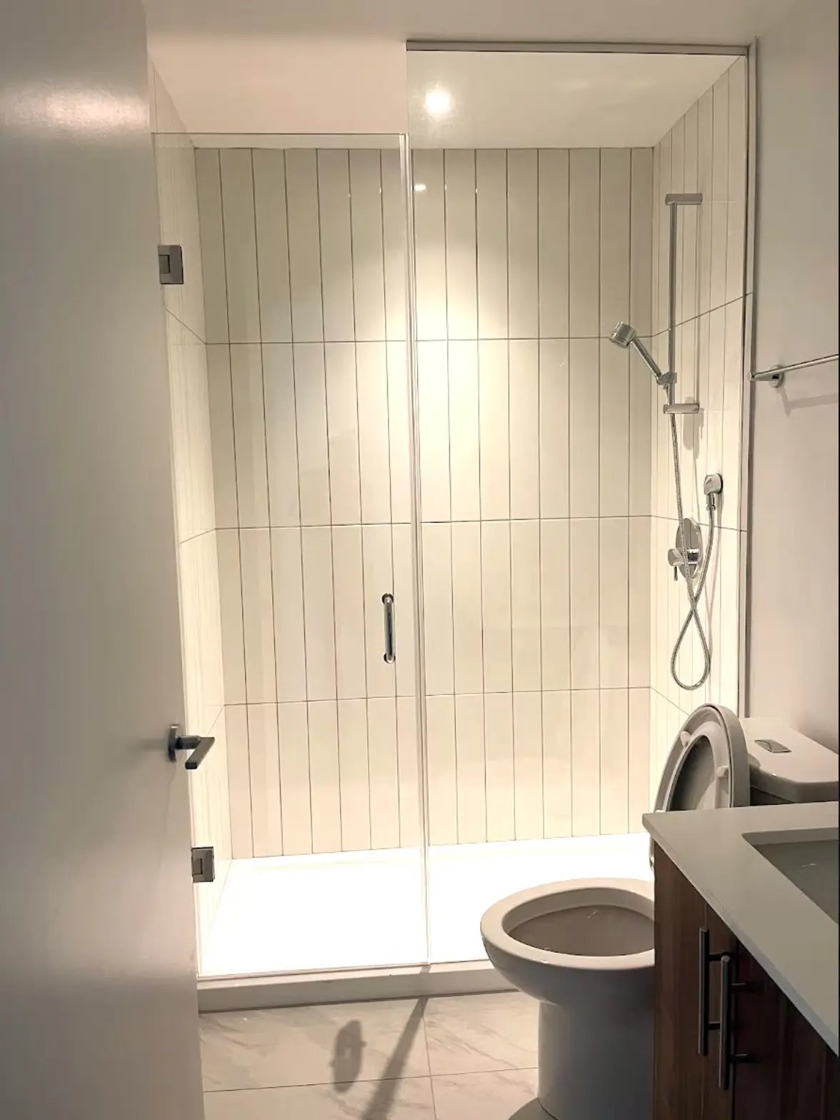 Completed basement bathroom with tile flooring, toilet, and finished walls