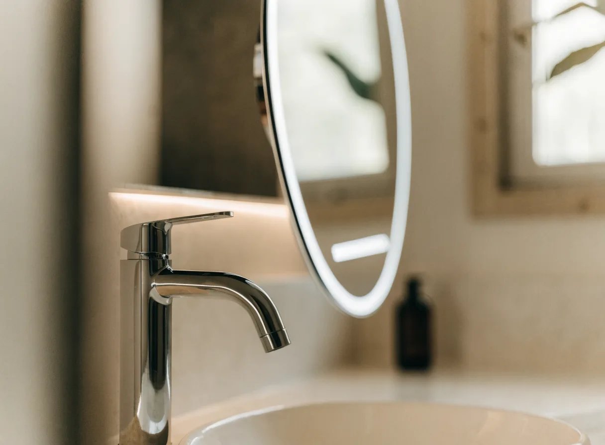 Chrome motion-sensor faucet and backlit smart mirror on a modern East York vanity