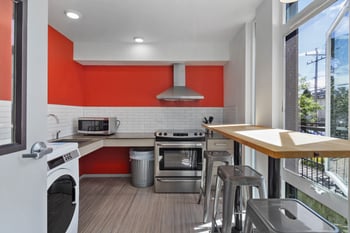 a kitchen with an orange accent wall and stainless steel appliances