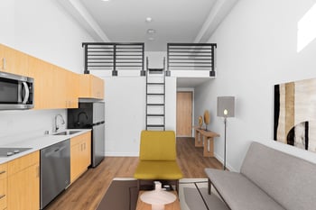 an open living room with a kitchen and a loft bed