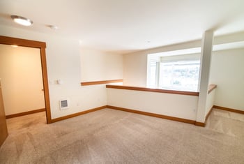 Union Bay Lofts Seattle rental: modern living room with large window, hardwood floors, and built-in storage.