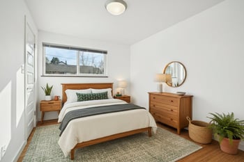 A bedroom with a bed, nightstand, and a plant.