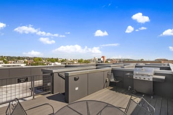 the rooftop of a building with barbecue grill and tables