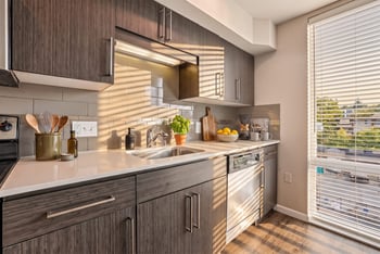 Kitchen counter with dark textured wood cabinets, white quartz countertop, undermount sink, and dishwasher.