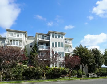 A large white apartment building with balconies and multiple windows.