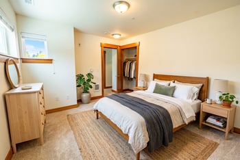 Bedroom with wood-framed bed, nightstands, dresser with mirror, and an open closet.