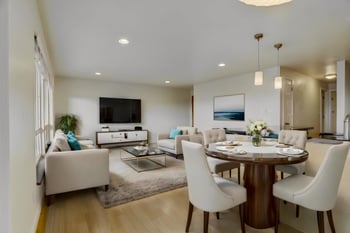 Dining area with a table and chairs, adjacent to a living room with sofas.
