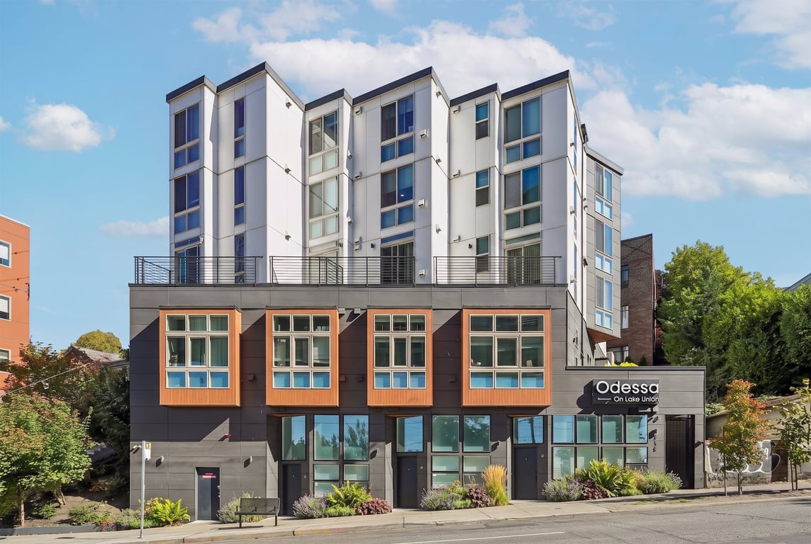 Odessa Apartments exterior with white and dark grey facade, large windows, and balconies.