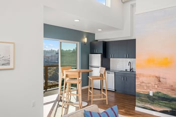 Kitchen with dark cabinets, stainless steel appliances, dining bar, and balcony access at Harbor ...