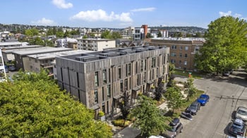 Bright living room with large windows and neutral decor in a Seattle apartment at 5902 Ballard Ave NW.