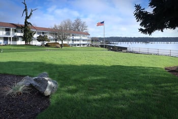 a grassy area with a flagpole and a building in the background