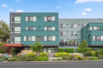 Exterior of Lanterman Apartments, a three-story teal and gray building with the Lanterman sign at the entrance.