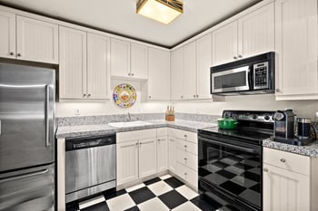 Kitchen with white beadboard cabinets, granite counters, stainless steel appliances, and checkere...