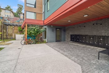 Paved building entrance at 609 with resident mailboxes, a bench, and a bicycle parked alongside.