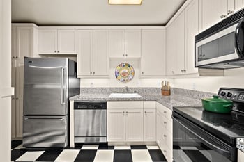 Kitchen with light cabinets, granite counters, stainless steel appliances, and black and white ch...