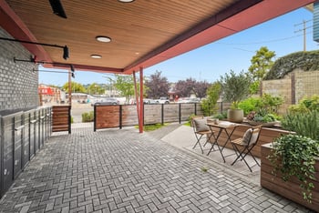 Covered courtyard with a wood ceiling, resident mailboxes, bistro seating, and raised planters.