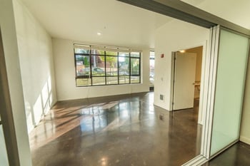 Bright living room at Vibe Apartments Seattle with modern kitchenette, sunny windows, ample storage.