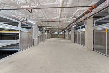 the inside of a building with a long concrete floor and steel cages