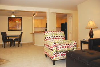 Bright living room with large window, modern seating and hardwood floors at Chianti Apartments, Renton, WA.