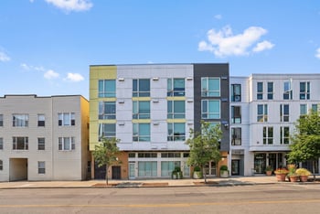 Street view of modern exterior facade at Ludwig Apartments under a blue sky with light clouds.