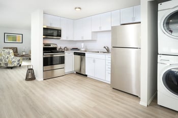 a kitchen with white cabinets and stainless steel appliances and a washer and dryer
