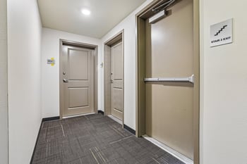 Interior corridor at Ludwig Apartments with unit doors and stairwell exit.