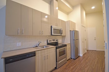 Bright living room in Larson Building apartment, Seattle, WA, featuring a modern kitchen and large window.