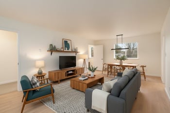 A living room with a grey couch, a green chair, a wooden coffee table, and a television.