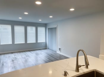 A kitchen counter with a sink and a window with blinds.