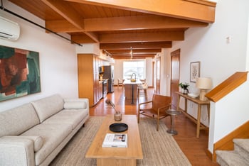 Open living room with exposed wood ceiling beams looking toward the kitchen island.