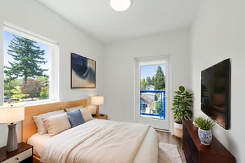 Bedroom with light wood bed frame, nightstands, lamps, wall-mounted TV, window, and balcony door.