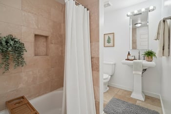 A bathroom with a beige tiled shower and a white toilet.