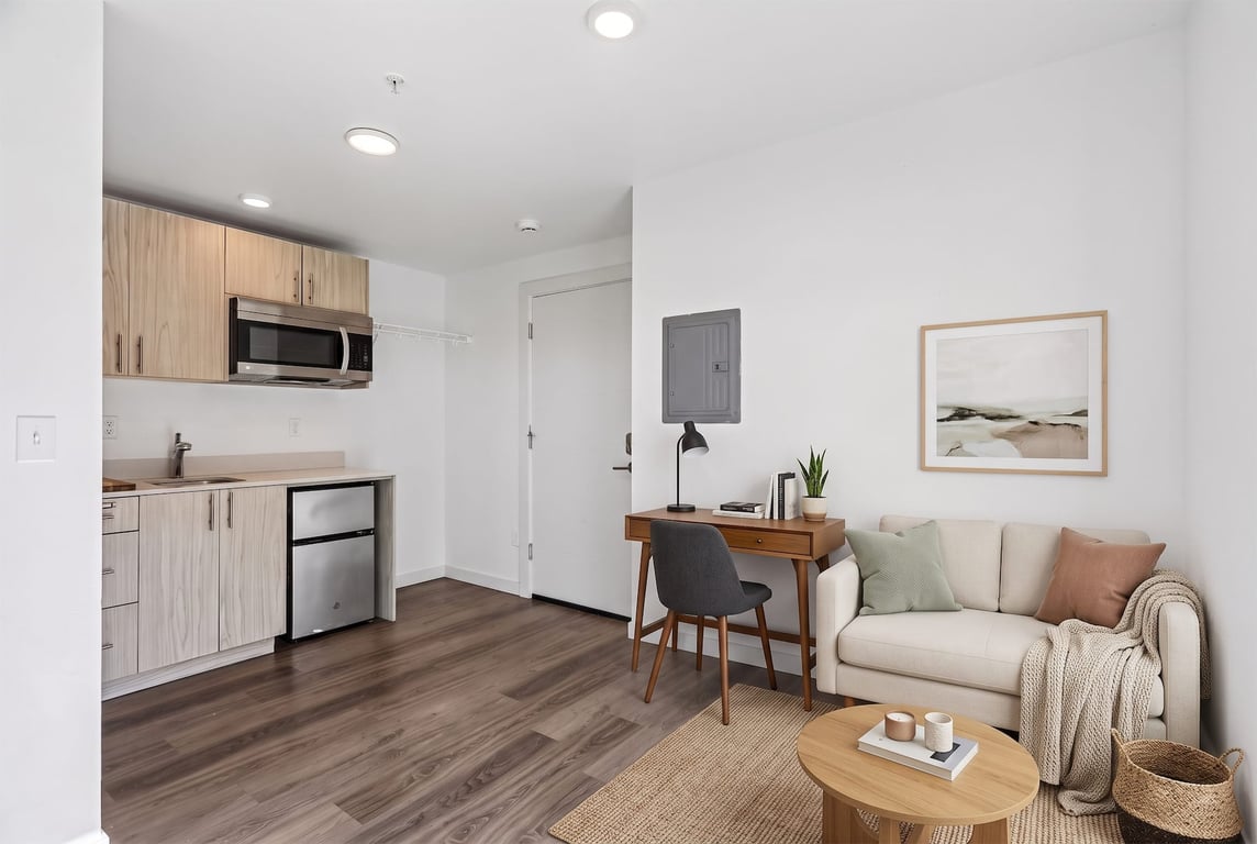Studio apartment featuring a kitchenette with microwave and mini-fridge, a desk, and living area ...