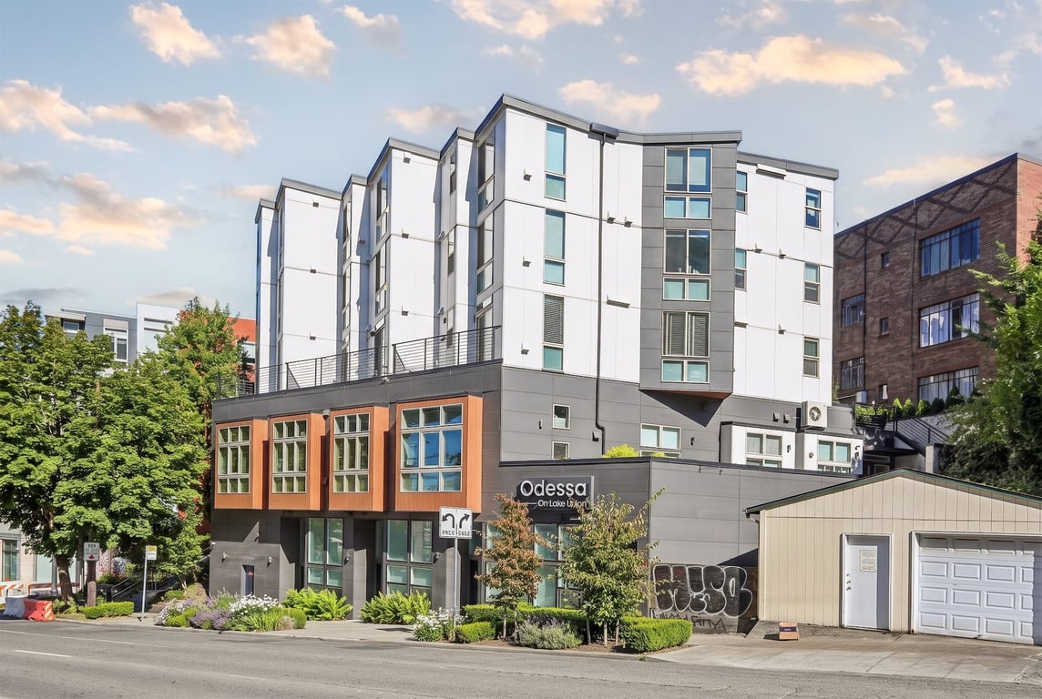 Modern Odessa apartment building exterior with white and grey facade, street, and green landscaping.
