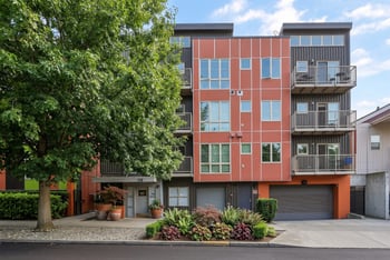 Exterior view of REV Fremont featuring terracotta and dark siding, private balconies, and ground-level entrance.