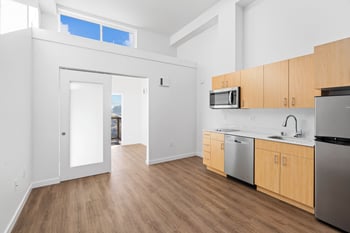 an empty kitchen with wood flooring and stainless steel appliances