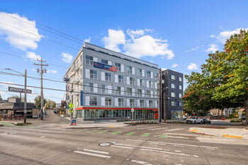Modern gray and black exterior of Keystone Apartments at a Seattle street corner, with signage an...
