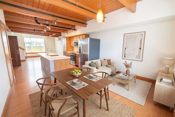 Open-concept apartment with wood beam ceiling, dining set, living area, and kitchen island.