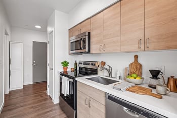 Kitchen with wood-tone cabinets, white counters, and a stainless steel range, microwave, and dishwasher.