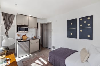 a bedroom with a bed and a kitchen with stainless steel appliances