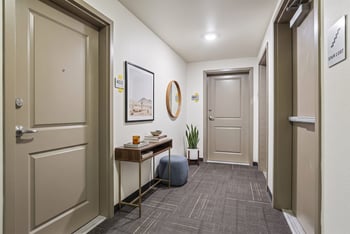 Well-lit apartment hallway with doors 401 and 402, patterned carpet, and a small decorative table.