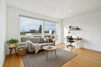 A living room with a grey couch, a wooden coffee table, a potted plant, and a chair.