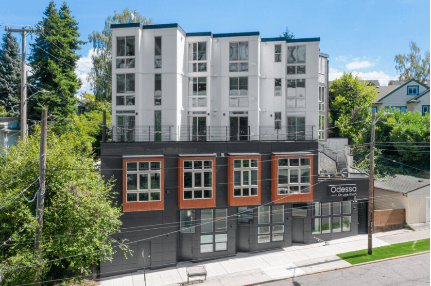 Exterior view of Odessa Apartments building in Seattle, featuring modern white and dark gray arch...
