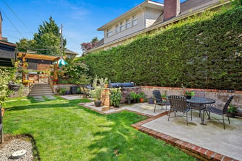 Community courtyard with green lawn, patio furniture, built-in BBQ, and lush hedges at East Highl...