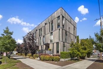 a gray building with a sidewalk and trees in front of it