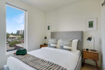 Interior view of a Werner Seattle rental apartment: sunny living area with modern kitchen and hardwood floors.